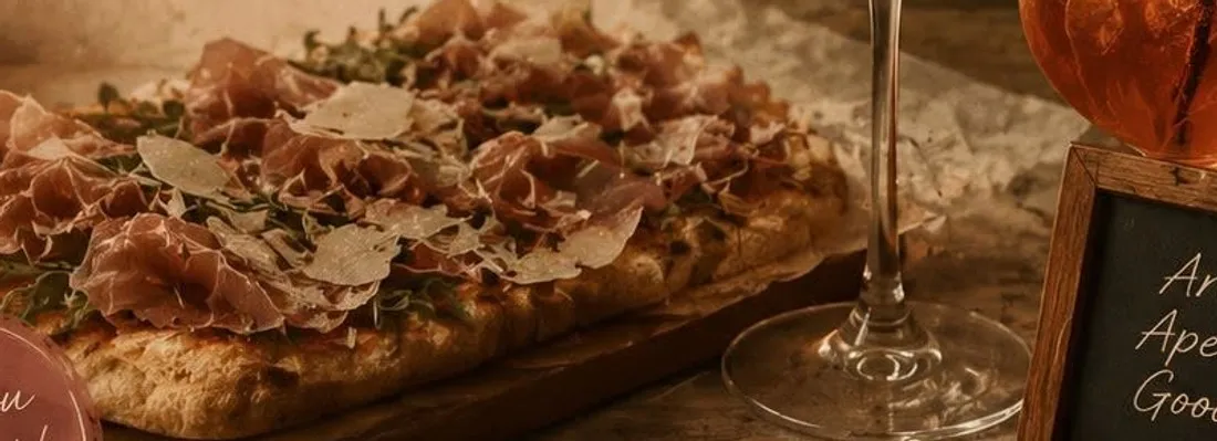 Prosciutto pinza with a glass of red wine and an orange spritz by candlelight